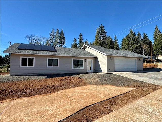 single story home featuring concrete driveway, solar panels, and a garage