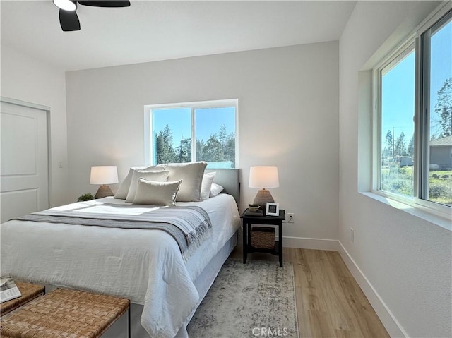 bedroom with a ceiling fan, baseboards, light wood finished floors, and a closet