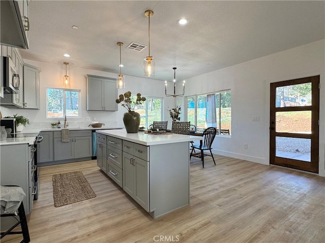 kitchen featuring a center island, gray cabinets, stainless steel microwave, and light wood-type flooring