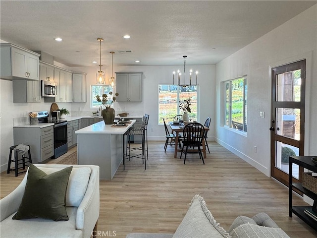 kitchen featuring an inviting chandelier, stainless steel microwave, range with electric cooktop, and gray cabinetry