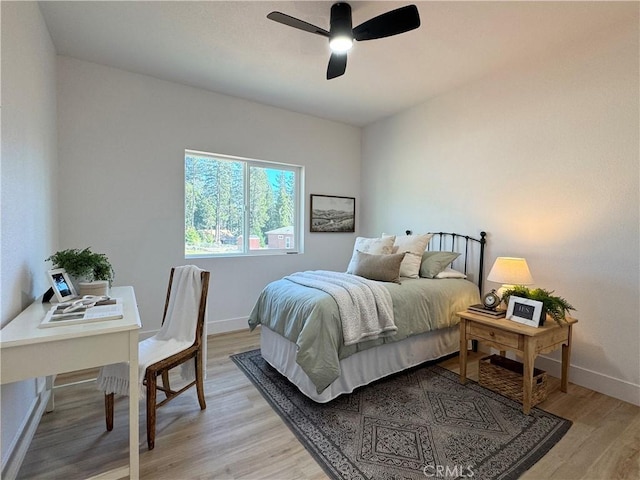 bedroom with light wood-style floors, a ceiling fan, and baseboards