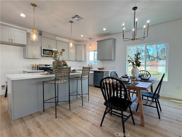 dining room featuring a notable chandelier, light wood-style flooring, and visible vents