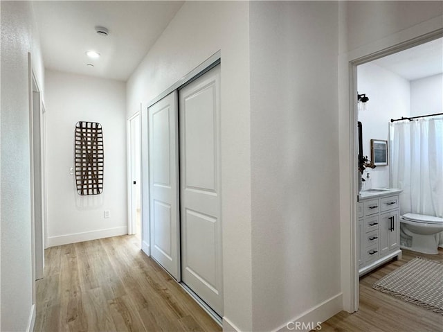 corridor featuring light wood-style floors and baseboards