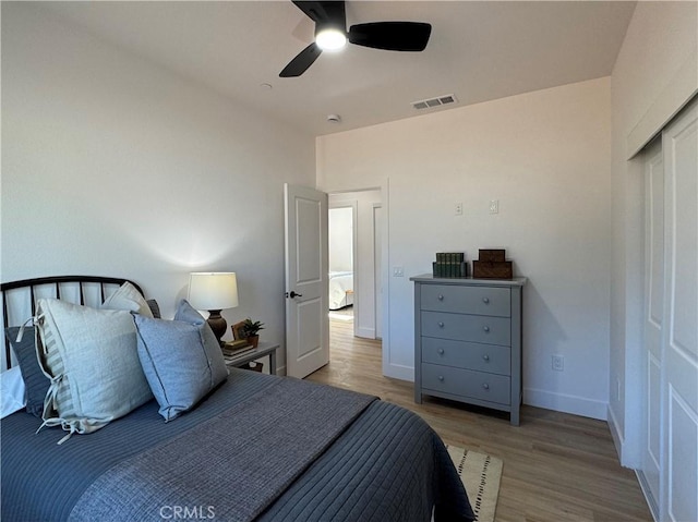 bedroom featuring a ceiling fan, baseboards, visible vents, and wood finished floors