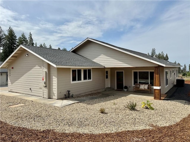 ranch-style house featuring roof with shingles and a patio area