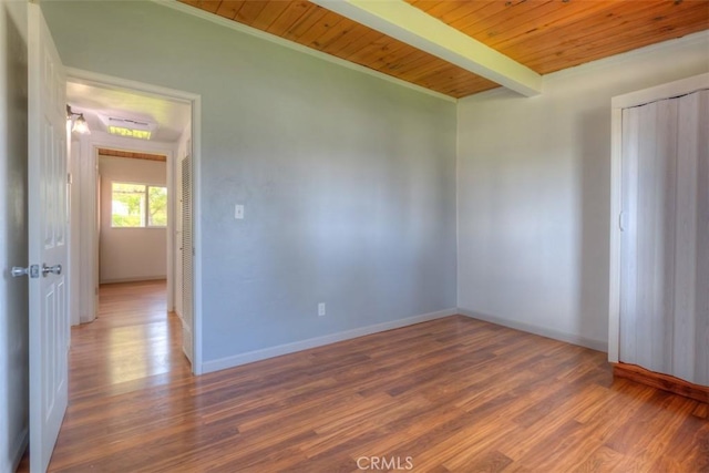 unfurnished room with baseboards, beamed ceiling, wood finished floors, and wood ceiling