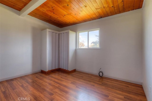 spare room with wooden ceiling, baseboards, beamed ceiling, and wood finished floors