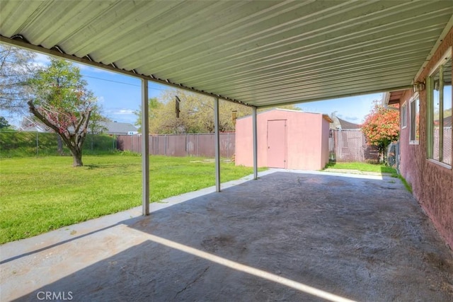view of patio with an outdoor structure, a fenced backyard, a storage unit, and a carport
