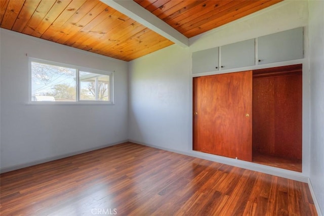 unfurnished bedroom with baseboards, wood ceiling, vaulted ceiling with beams, a closet, and wood finished floors