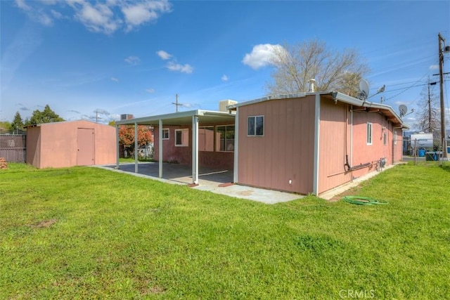 rear view of house with fence, a storage shed, an outdoor structure, and a yard