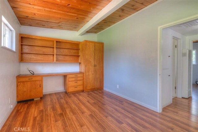 unfurnished office with built in desk, wood ceiling, and wood finished floors