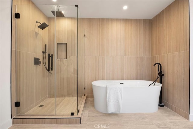 bathroom featuring a soaking tub, tile walls, and a stall shower