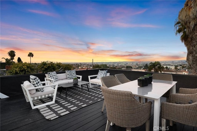 deck at dusk with outdoor dining space and an outdoor hangout area