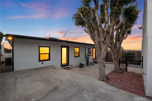 view of front of house with a patio area, stucco siding, and fence