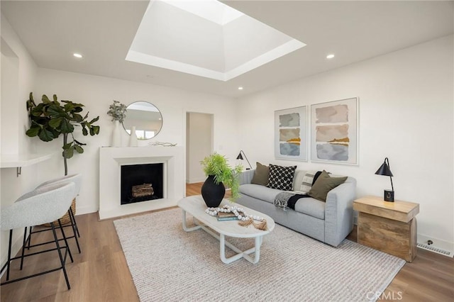 living room with recessed lighting, a fireplace, a skylight, and wood finished floors
