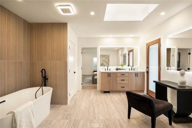 ensuite bathroom with a freestanding bath, wood finished floors, ensuite bathroom, and a sink