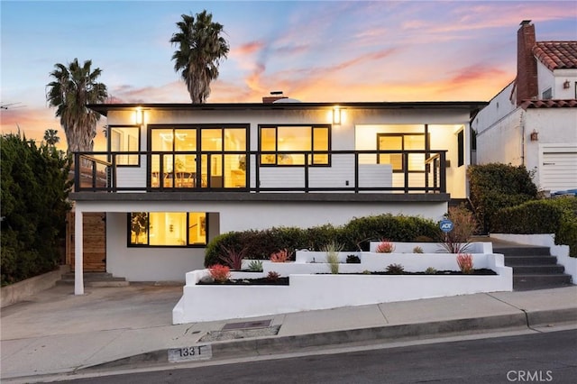back of property at dusk featuring stucco siding and stairs