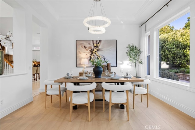 dining space featuring a raised ceiling, light wood-style floors, a chandelier, baseboards, and ornamental molding