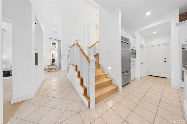 stairway featuring recessed lighting, a high ceiling, baseboards, and tile patterned floors