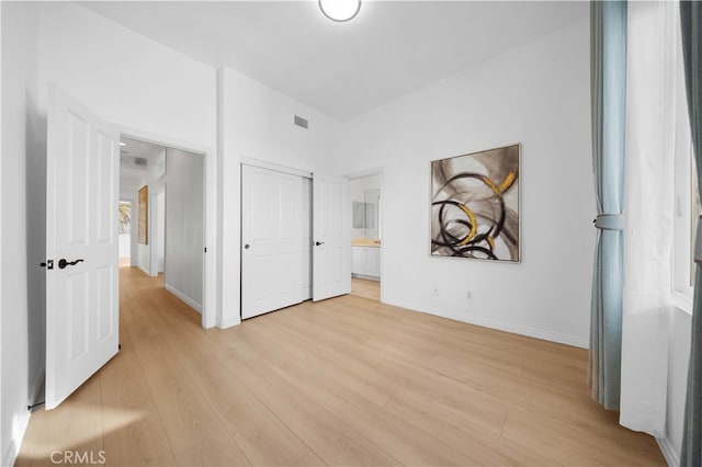 unfurnished bedroom featuring visible vents, a closet, baseboards, connected bathroom, and light wood finished floors