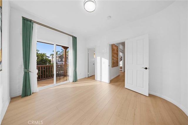 spare room with baseboards and light wood-style floors