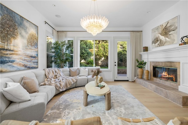 living room with a tiled fireplace, wood finished floors, and a chandelier