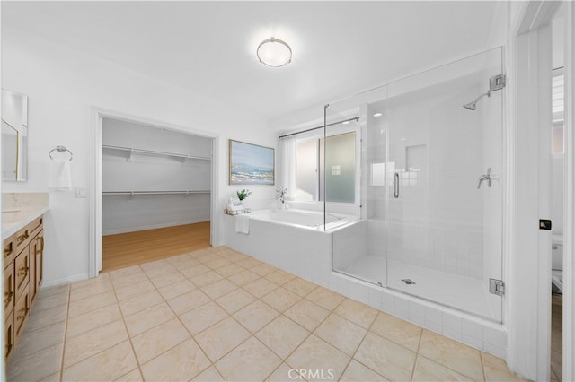 bathroom featuring a walk in closet, a garden tub, a shower stall, vanity, and tile patterned floors