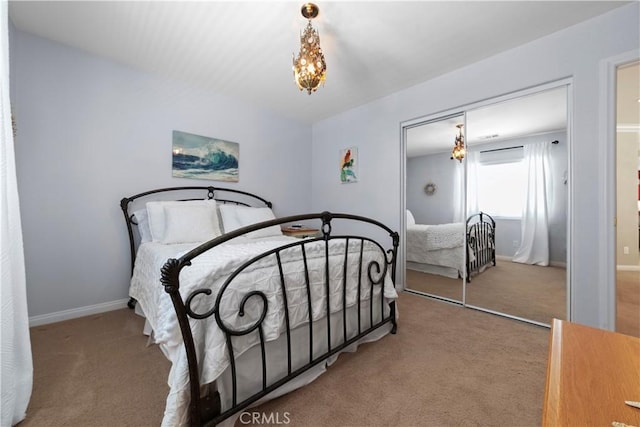 carpeted bedroom featuring a closet, baseboards, and a chandelier