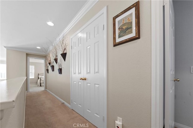corridor with crown molding, a textured wall, baseboards, light colored carpet, and recessed lighting