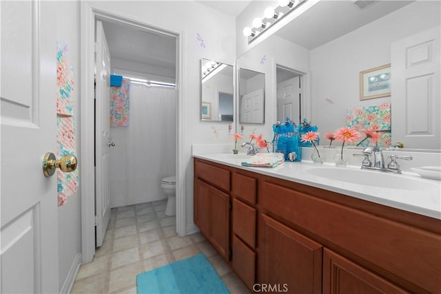 full bathroom featuring a sink, double vanity, toilet, and tile patterned floors