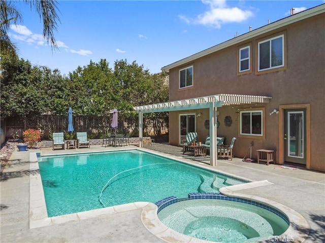 view of swimming pool with a patio, fence, and a pool with connected hot tub