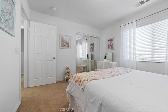 bedroom featuring a closet, baseboards, visible vents, and light carpet