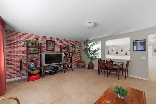 carpeted living area featuring baseboards and brick wall