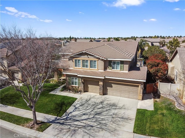 view of front facade with stucco siding, fence, an attached garage, a tiled roof, and driveway