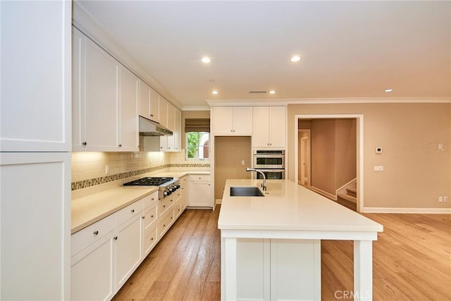 54 Trotter, Irvine, CA 92602 - kitchen with stainless steel appliances, under cabinet range hood, crown molding, backsplash, and a center island with sink