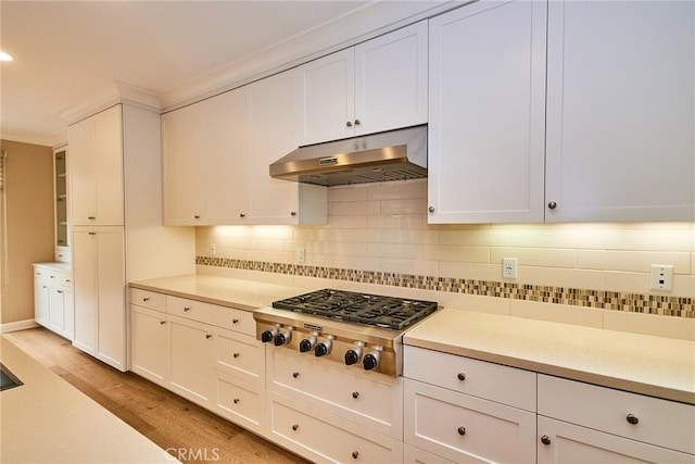 54 Trotter, Irvine, CA 92602 - kitchen featuring under cabinet range hood, stainless steel gas stovetop, backsplash, light wood-type flooring, and white cabinets