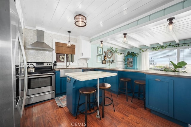 27 A Surfside Ave, Surfside, CA 90743 - kitchen with blue cabinets, stainless steel appliances, wall chimney range hood, dark wood-style floors, and a kitchen breakfast bar