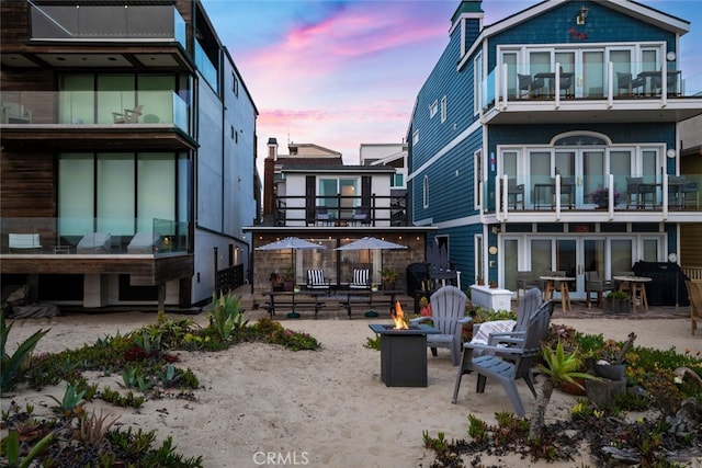 27 A Surfside Ave, Surfside, CA 90743 - back of house at dusk featuring an outdoor fire pit, a balcony, and a chimney