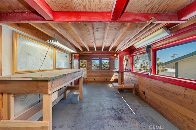 misc room featuring unfinished concrete floors and wooden walls
