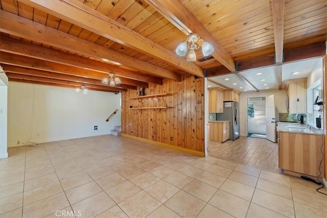 kitchen featuring open floor plan, light countertops, stainless steel fridge with ice dispenser, and beam ceiling