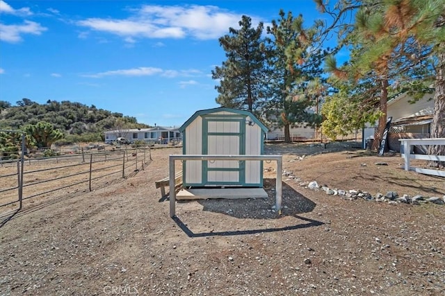 exterior space featuring a storage unit, an outdoor structure, and fence