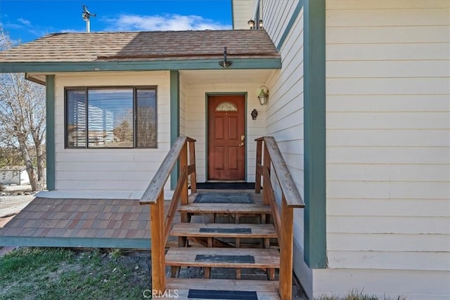 entrance to property featuring a shingled roof