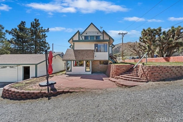 view of front of house with a patio, stairs, and a balcony