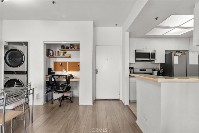 19350 Sherman Way Unit 204, Reseda, CA 91335 - kitchen featuring appliances with stainless steel finishes, stacked washing machine and dryer, light wood-style floors, white cabinetry, and light countertops