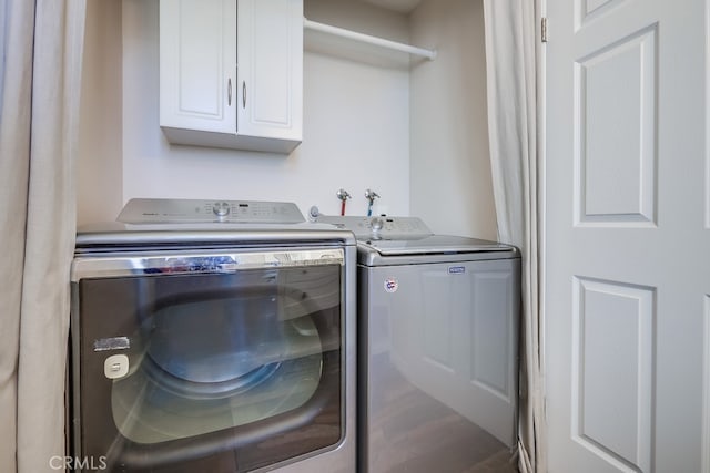 laundry area with separate washer and dryer and cabinet space
