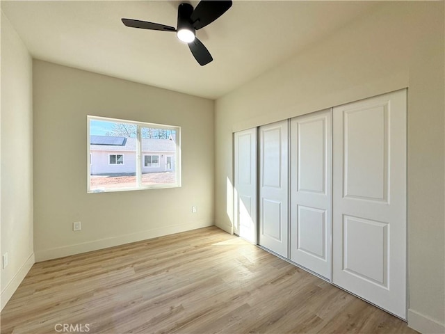 unfurnished bedroom featuring light wood-type flooring, a closet, a ceiling fan, and baseboards