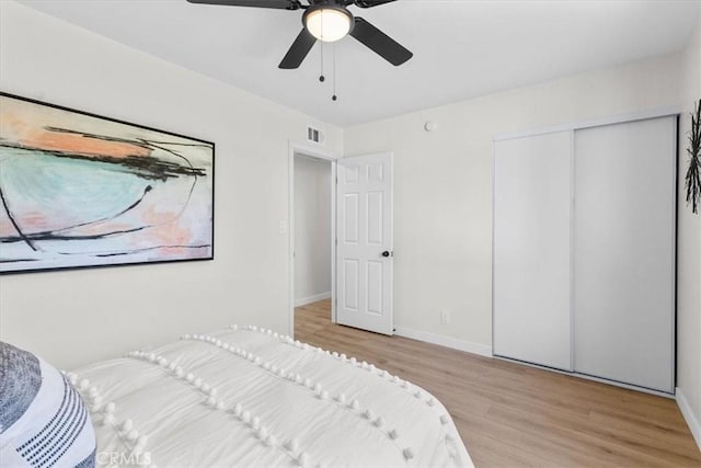 bedroom featuring baseboards, visible vents, a ceiling fan, a closet, and wood finished floors