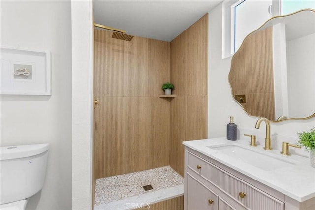 full bathroom with toilet, tiled shower, and vanity