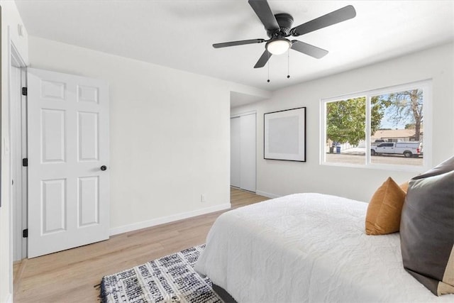bedroom with baseboards, a closet, wood finished floors, and ceiling fan
