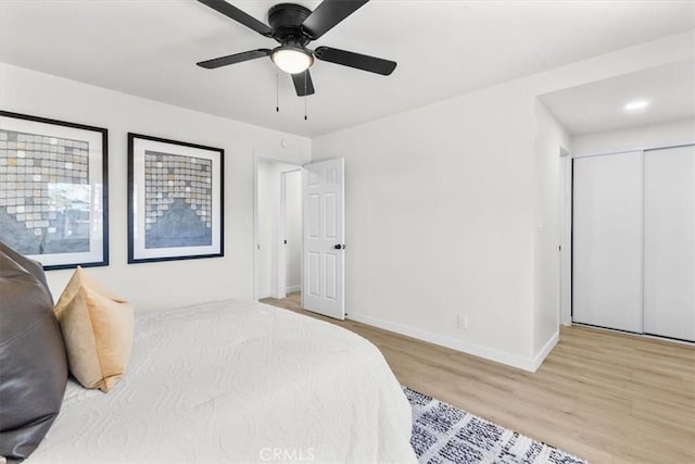 bedroom featuring a closet, baseboards, ceiling fan, and wood finished floors